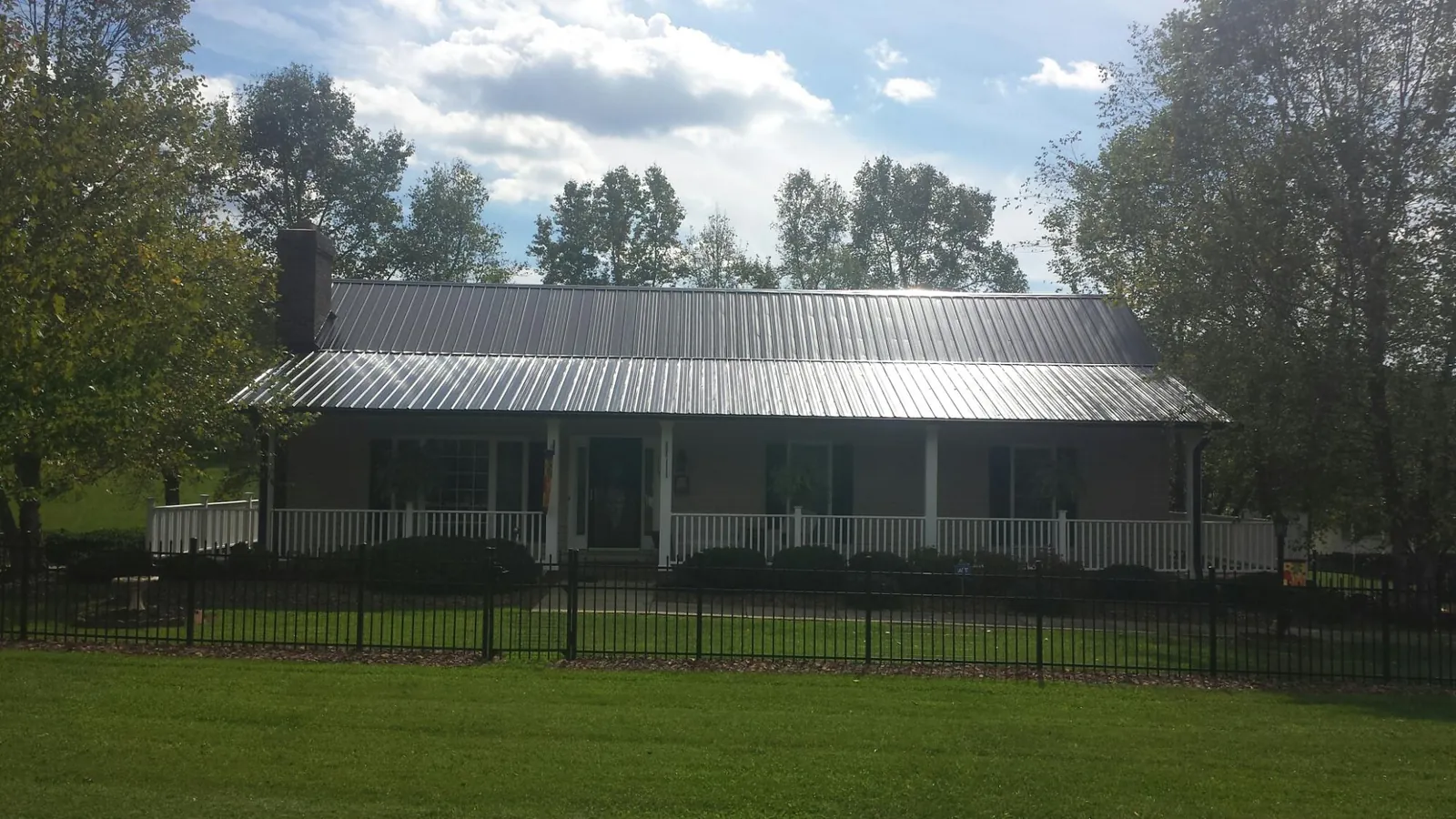 Gray metal roof on a brick ranch with a full width front porch — Gutter Guard Installation work by our crew in Romulus